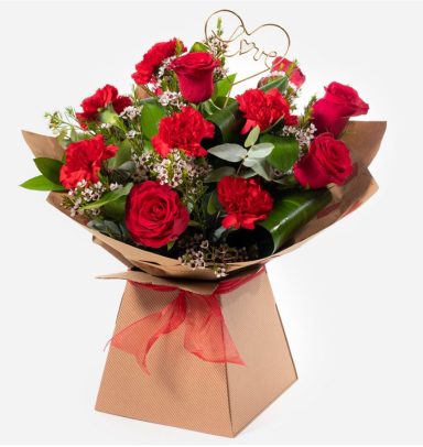 A bouquet of red roses and carnations arranged in a decorative kraft paper wrap.