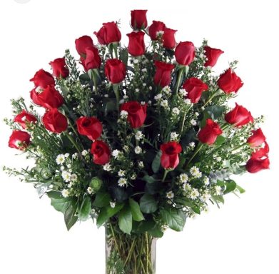 A bouquet of red roses surrounded by white flowers and greenery in a vase.