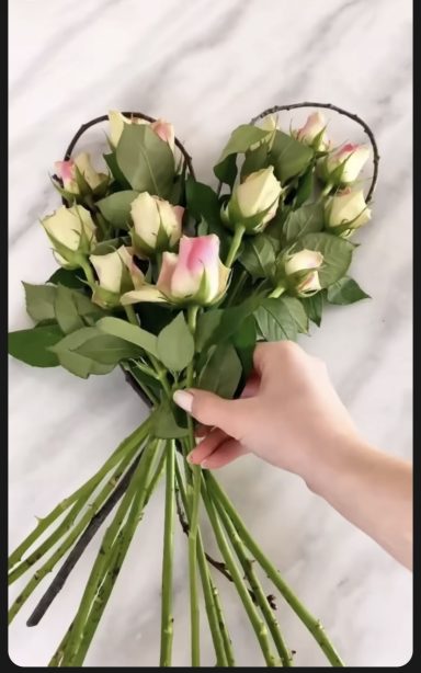 A bouquet of pink-tipped white roses arranged in a heart shape.