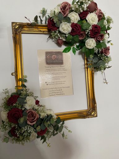 A decorative frame adorned with red and white flowers, presenting a certificate.