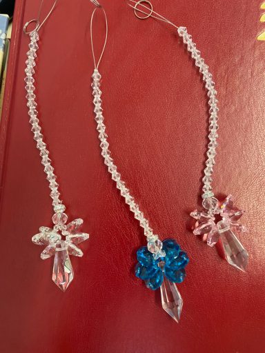 Three beaded earrings featuring clear, blue, and pink floral designs.