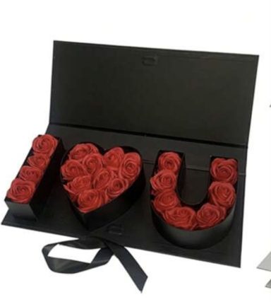 Red roses arranged in the shape of "I Love You" in a black box.