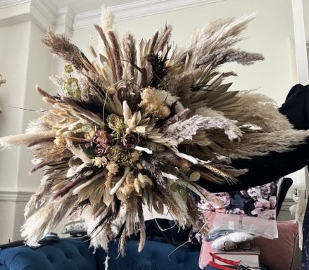 A decorative bouquet made of dried grasses and flowers in neutral tones.