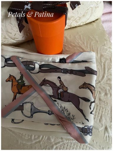 A patterned cloth with horse and riding motifs, alongside an orange pot.