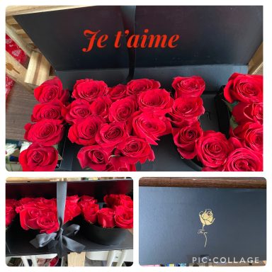 A bouquet of red roses in a black box with "Je t'aime" written on the lid.