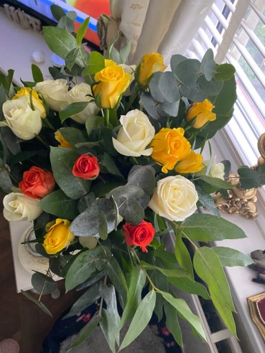 A vibrant bouquet featuring white, yellow, and red roses with green foliage.