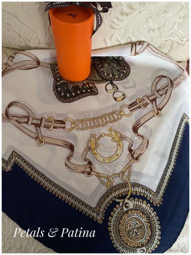 A decorative scarf with intricate patterns and a stylish orange cup on top.